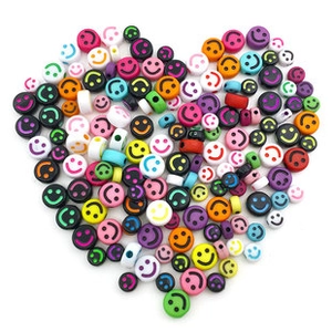 Close-up of heart-shaped arrangement of colorful acrylic smiling face beads for DIY jewelry