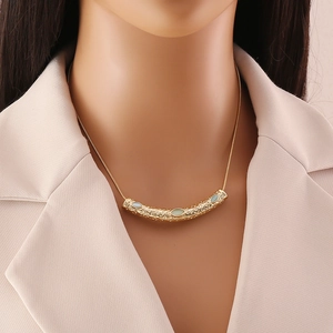 Detail of gold metal textured bar necklace with three oval light blue stones on model