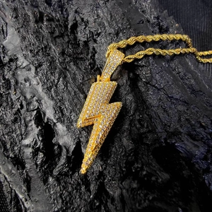 Macro shot of gold lightning bolt pendant with sparkling zircons on a rope chain