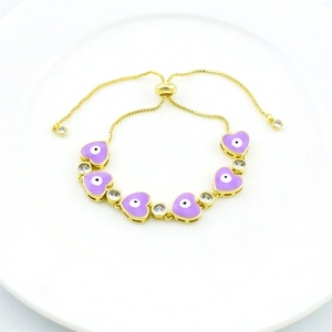 Detail of gold evil eye bracelet with purple enamel heart charm and clear zircon stones
