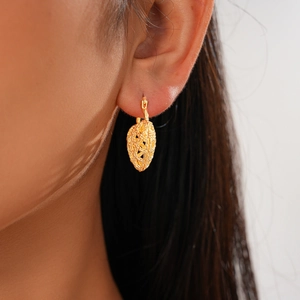 Macro shot of gold hollow woven heart earrings showing intricate metallic texture and craft