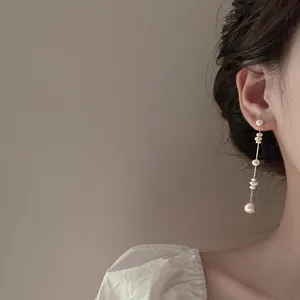 Close-up of French vintage long dangle earrings with white freshwater pearls on a model