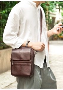 Vertical dark brown leather crossbody bag with multiple zip pockets on male model