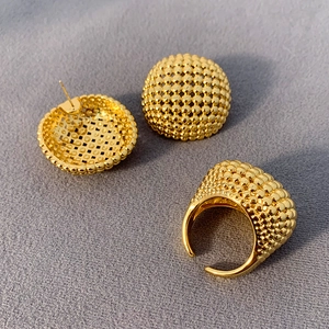 Makroaufnahme von Goldschmuck-Set mit strukturierten Ohrringen und verstellbarem Ring