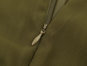 Macro detail of high-quality invisible zipper on olive green pleated chiffon dress
