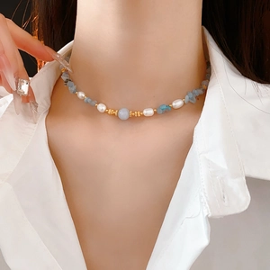 Detail of freshwater pearl necklace with blue stones and a central round bead pendant