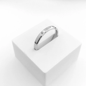 Macro shot of minimalist titanium steel ring with a single diamond inlay on a white stand