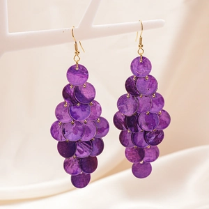 Detail showing layered purple shell sequins and gold hooks on a jewelry stand