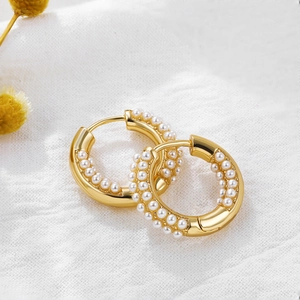 18K gold hoop earrings with turquoise accents and rows of white pearls on fabric