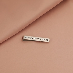 Macro detail of stainless steel tie clip engraved with Father of the Bride lettering