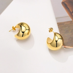 Close-up of chunky gold C-shaped hoop earrings with a high-polished mirror finish