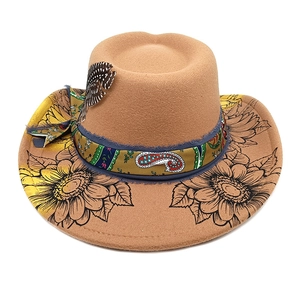 Détail du chapeau en feutre avec ruban paisley, plume et motif floral sur le bord