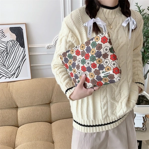 Gros plan détaillé d'une trousse à maquillage en velours côtelé à fleurs tenue par un modèle