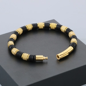Detail view of gold-tone metal clasp with diamond texture on black woven leather bracelet
