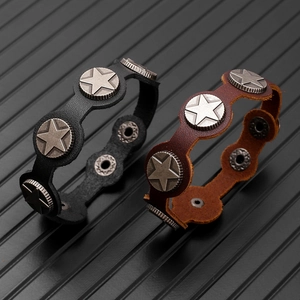 Detail view of black and brown leather bracelets featuring star engraved metal rivets