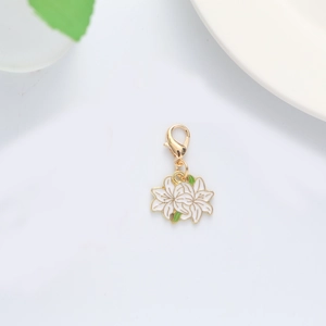 Close-up of white enamel flower keychain with gold plating and green leaf detail