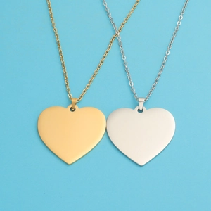 Close-up of heart-shaped stainless steel pendants in gold and silver on blue background
