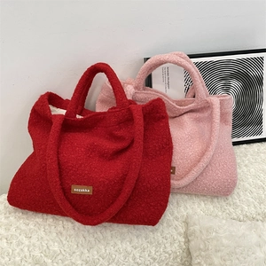 Dettaglio di borse tote in pile rosso e rosa con etichette in pelle su tappeto morbido