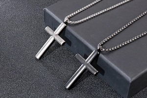 Close-up of black and silver matte cross pendants on metal pearl chains for couples