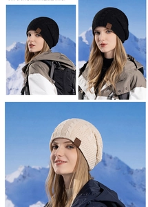 Detail of cable knit texture and brown leather patch on black and beige winter beanies