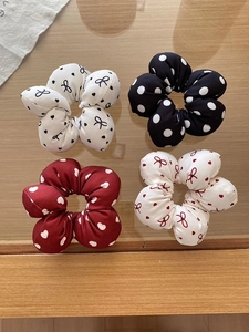 Flat lay of four floral scrunchies with heart and polka dot prints on wood