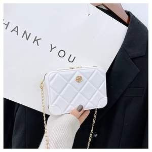 Macro shot of white quilted PVC jelly bag with gold chain and floral clasp detail