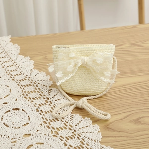 Détail d'un mini sac bandoulière tissé beige orné d'un grand nœud en dentelle à pois