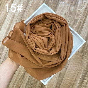 Détail de la texture d'une écharpe en mousseline caramel pliée en forme de rose