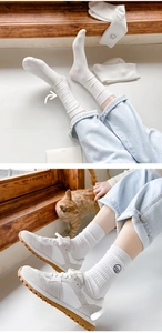 Detail of white ribbed cotton socks featuring cute cartoon animal embroidery on the side