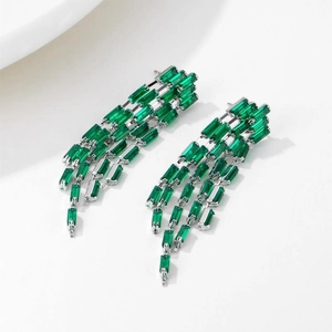 Exaggerated silver tassel earrings with emerald green baguette cut zircons in a cascade design