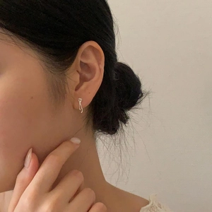 Close-up of a minimalist silver bow earring on a model showing sleek metal texture