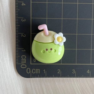 Detailed top view of a mini green coconut drink resin charm on a grid cutting mat