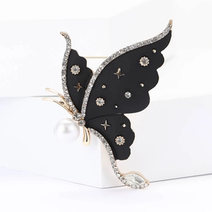 Macro detail of alloy butterfly brooch with black rhinestones, star motifs and a pearl drop