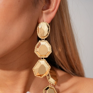 Close-up of golden geometric multi-layer drop earrings with hammered metal texture