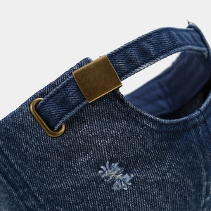 Detailed close-up of washed denim baseball cap with vintage brass metal adjustment buckle
