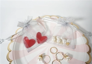 Detail of silver grey organza drawstring jewelry bag with pearl and heart pendant inside