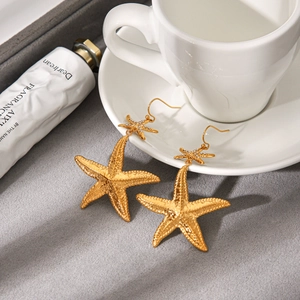 Detail of gold starfish earrings with sparkling crystal accents and textured metal finish