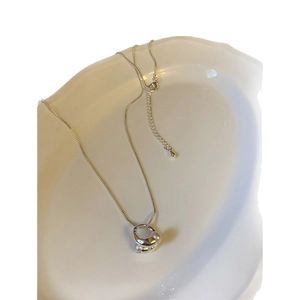 Collana d'argento con pendente a nodo perlato e catena regolabile su piatto ceramica