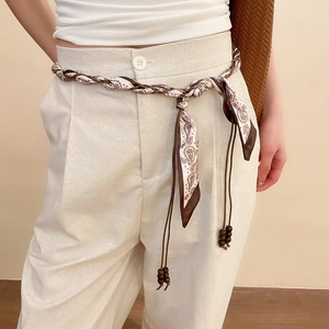 Detail of vintage fabric waist chain with wood beads on linen trousers for women