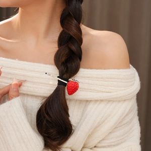 Dettaglio di un grazioso accessorio per capelli a fragola rossa su un'acconciatura a treccia