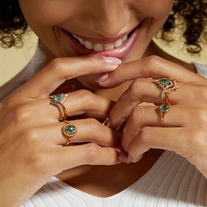 Close-up of elegant gold S925 rings with green moss agate and zircons on a model