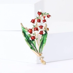 Detail of lily of the valley brooch with red enamel flowers and green leaves decoration