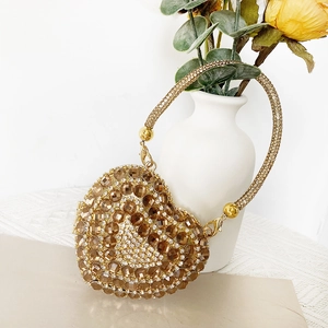 Close-up of golden heart-shaped evening bag with sparkling rhinestones and chain strap