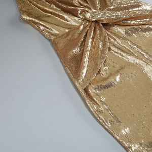 Detailed view of the gold sequin fabric with a central twist knot design on the jumpsuit