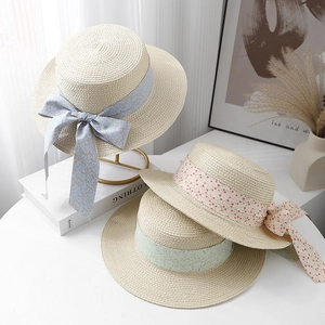 Three summer straw boater hats with floral ribbon bows in blue, green, and pink colors