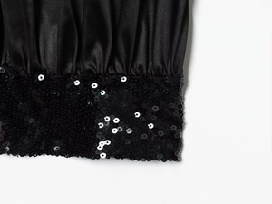 Detailed view of black satin fabric with sequin embellishments and elegant pleats
