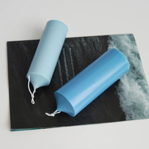 Detail of blue cylindrical candles on wave pattern card for DIY candle making molds