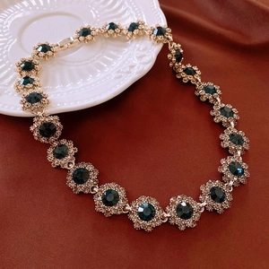 Detail of French court style gold necklace with emerald blue round stones and crystals