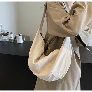 Beige large nylon crossbody dumpling bag shown in a lifestyle coffee scene context