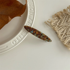 Detail showing tortoise shell pattern resin hair clip on a white ceramic plate